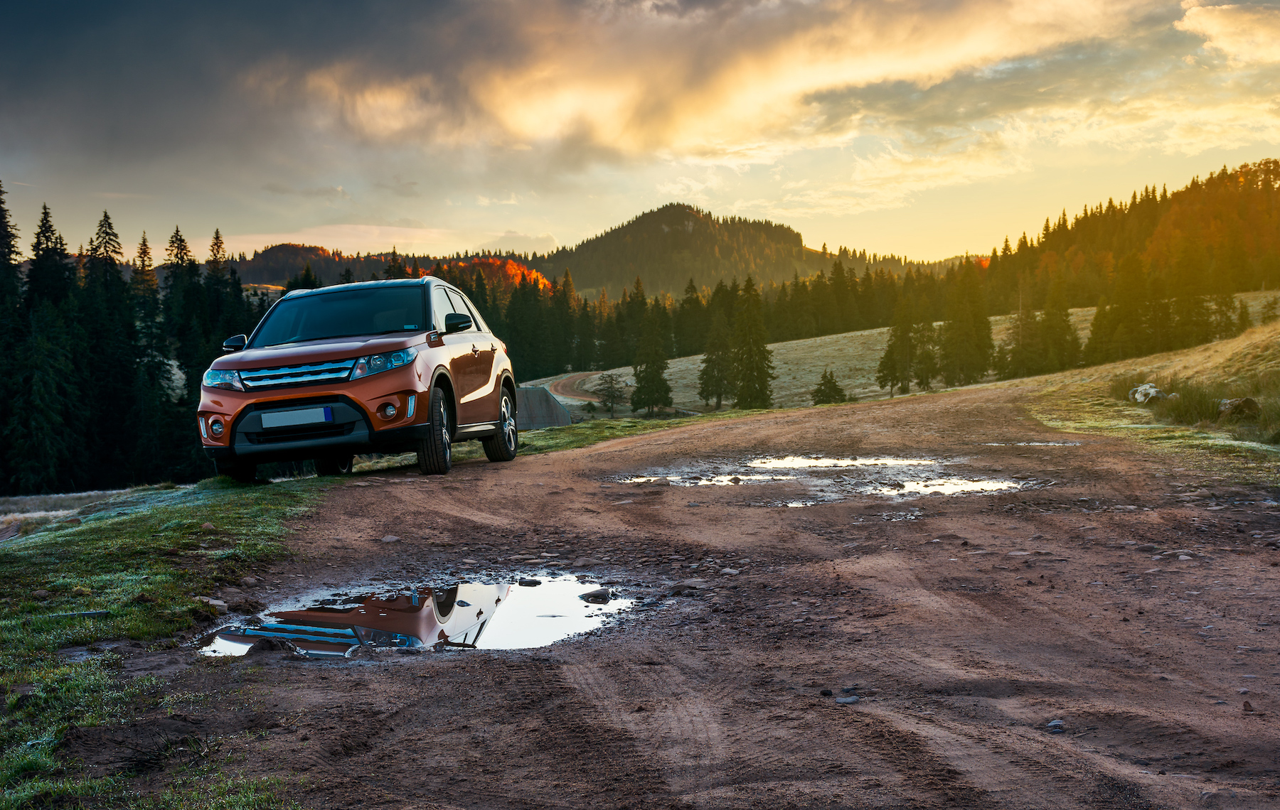 Red conventional powertrain SUV driving off road