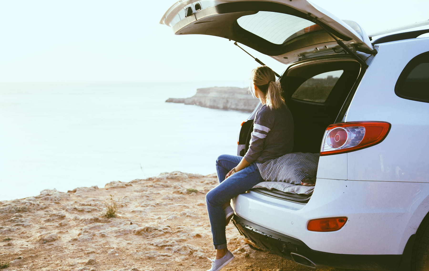 girl sitting in a car looking at the ocean